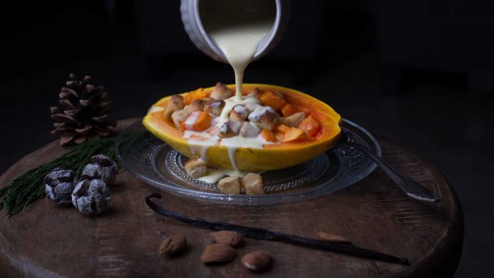 Ein LCHF Dessert: auf eine gebackene Papaya, gefüllt mit Marzipan, wird Vanillesosse gegossen