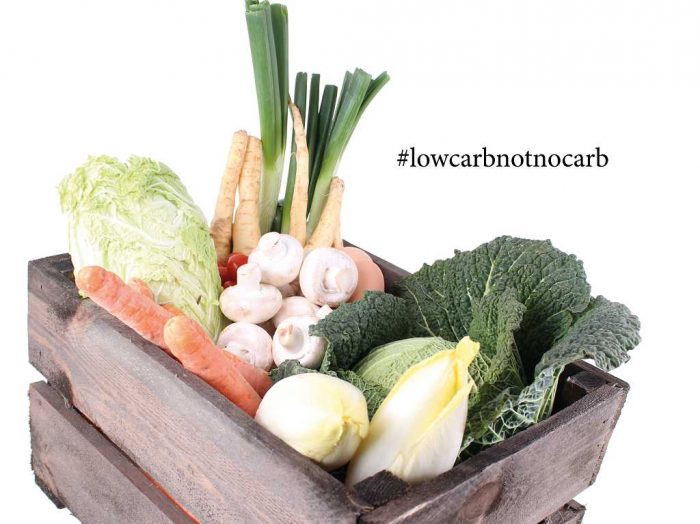 Ein Holzkorb, gefüllt mit Gemüse. Darüber das Hashtag #lowcarbnotnocarb