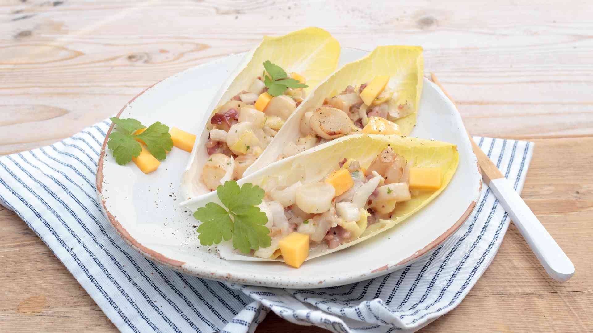 Schwarzwurzel-Pfanne mit Papaya, Speck und Chicoree auf einem Teller